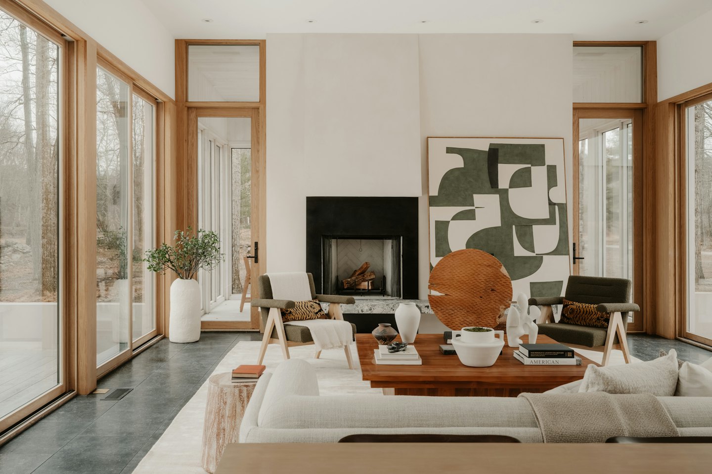 Modern living room with large windows and black fireplace.