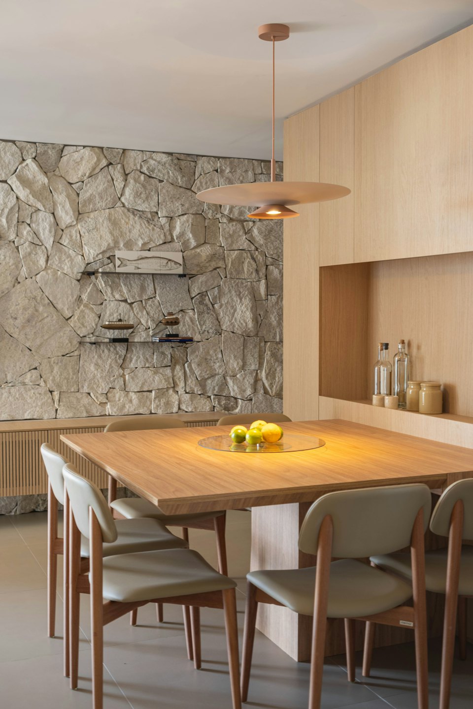 Modern dining area featuring a wooden table and stone wall.