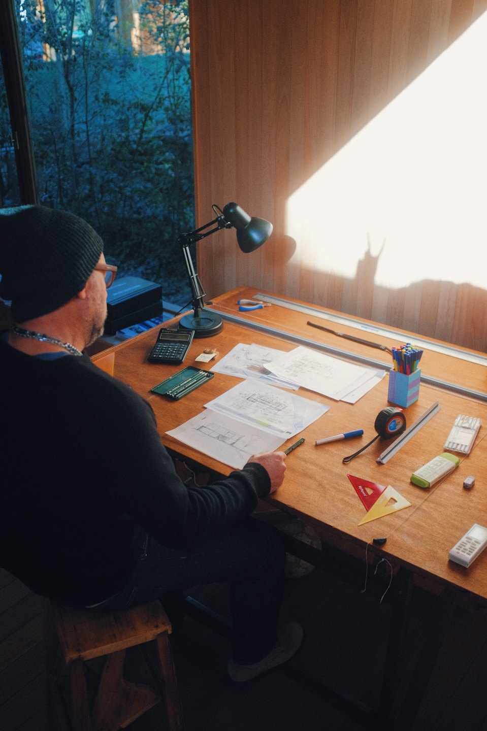 Architect working on blueprints at a sunlit drafting table.