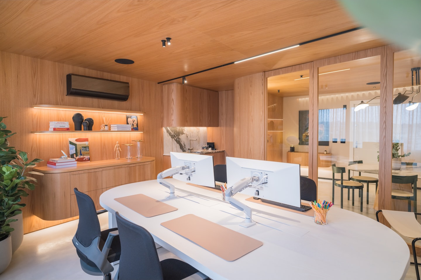 Modern office with white oval desk and computers.